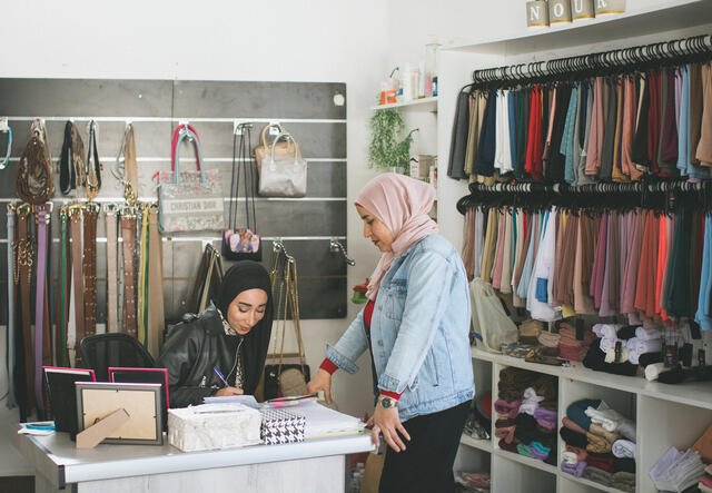 Nour sits at a desk in her store.